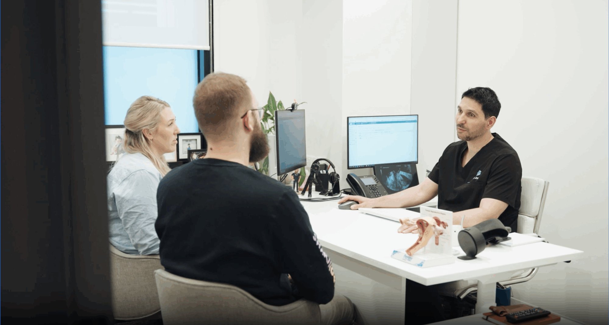 Two people talking with a clinician in a consulting room